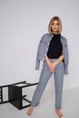 Woman in Checkered Blazer and Pants Standing Next to Tipped Over Chair