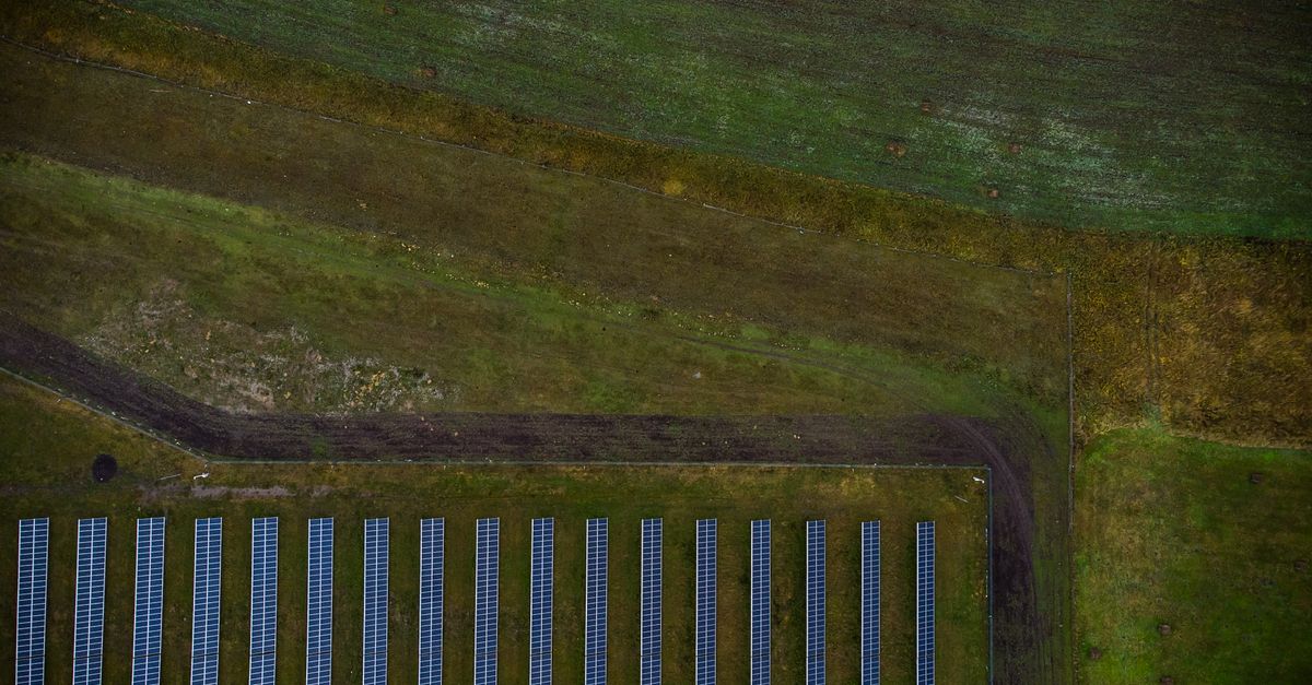 Luftaufnahme einer Solaranlage auf landwirtschaftlichen Feldern in grĂĽner Landschaft