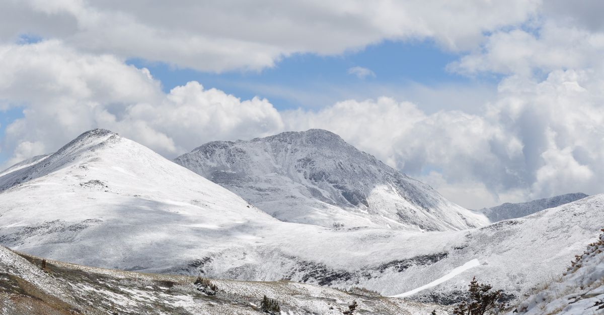 Stunning view of snow-covered mountains under a cloudy sky in the Colorado Rockies.