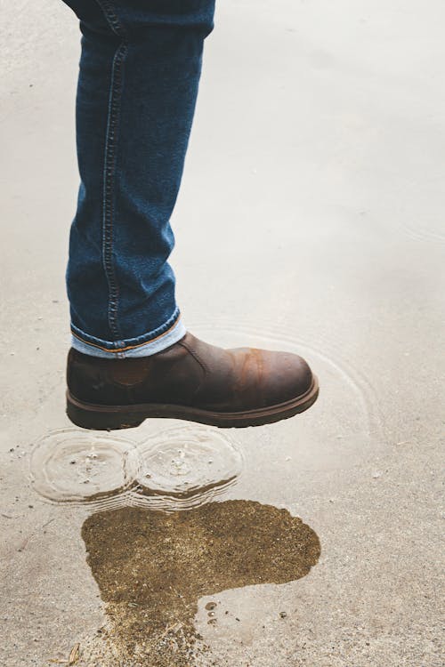 Leg in Leather Brown Chelsea Boots over Rain Pool