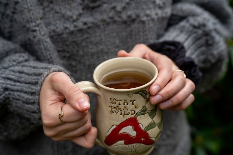 A Person Holding A Cup Of Tea