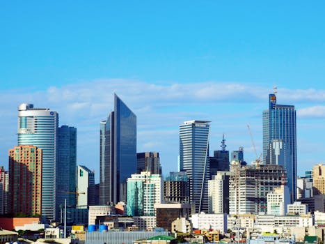 Bright daytime view of Makati City's modern skyline featuring prominent skyscrapers under a clear blue sky.