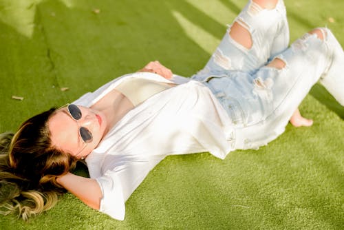 Woman in White Shirt Wearing Sunglasses Lying on the Ground