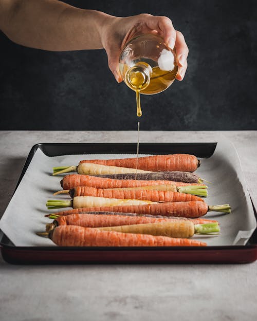 Olive Oil Being Poured on Fresh Carrots