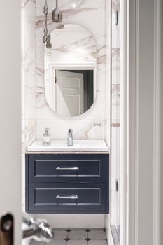 Sleek bathroom with marble tiles and stylish round mirror in Saint Petersburg.