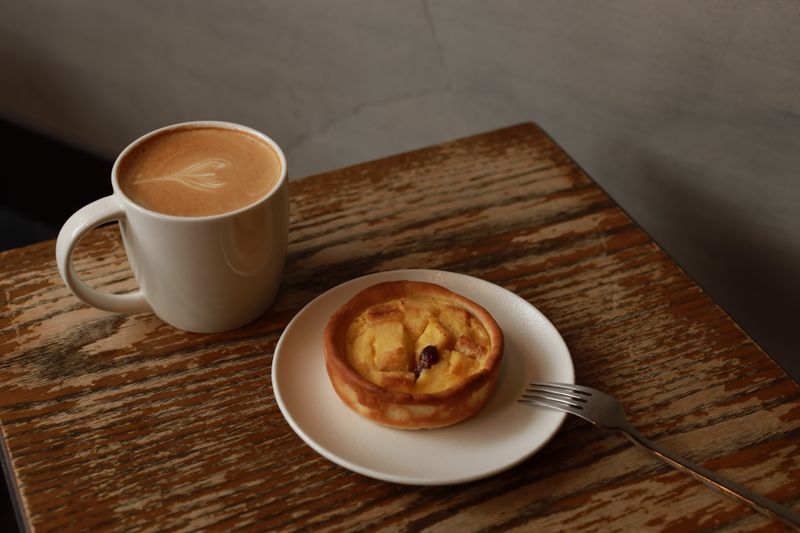 A warm coffee cup and pastry on a rustic table, perfect for cozy café moments in Taipei.