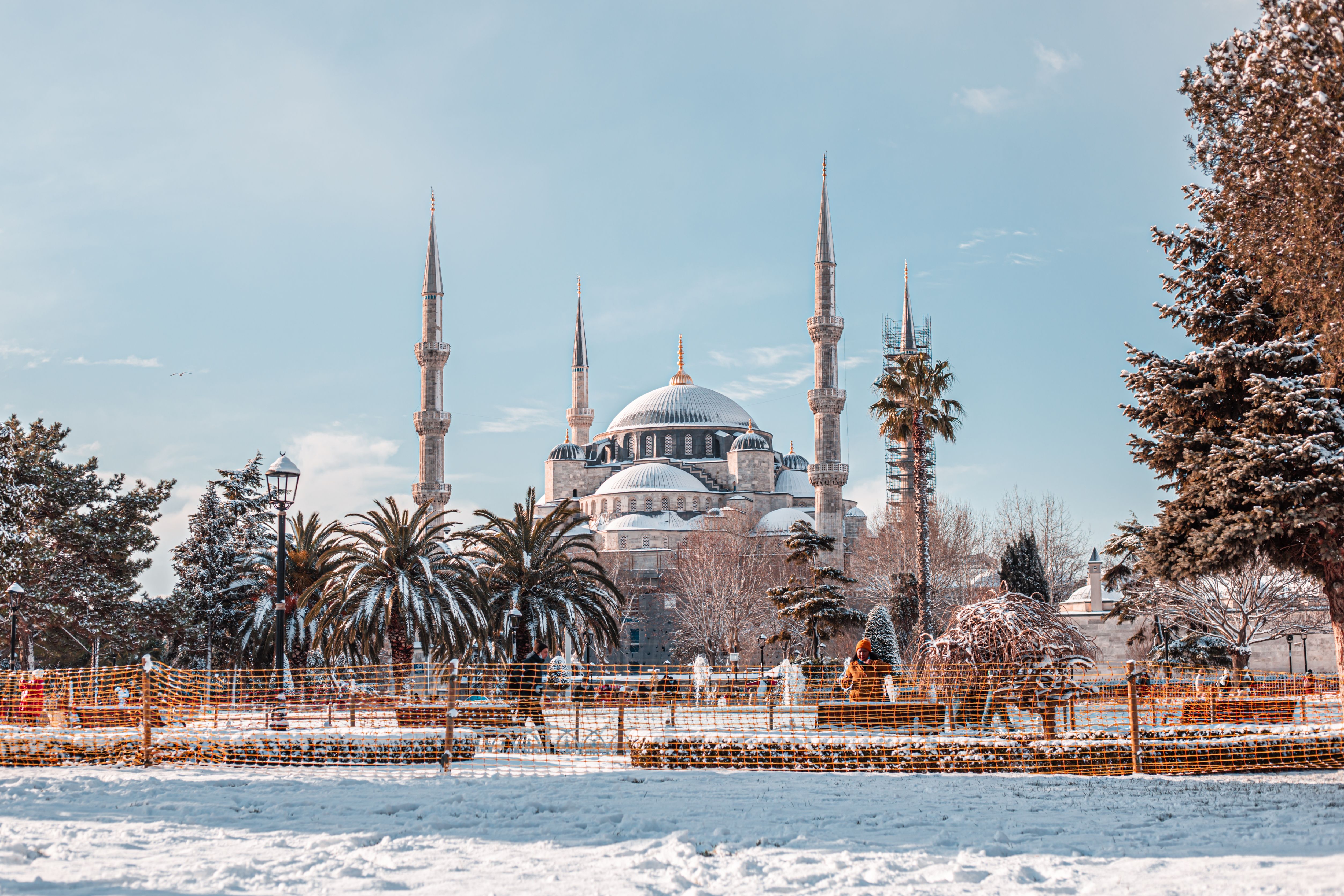 A captivating winter scene of the Sultan Ahmed Mosque in Istanbul, Turkey, with snow-covered ground and clear blue sky.