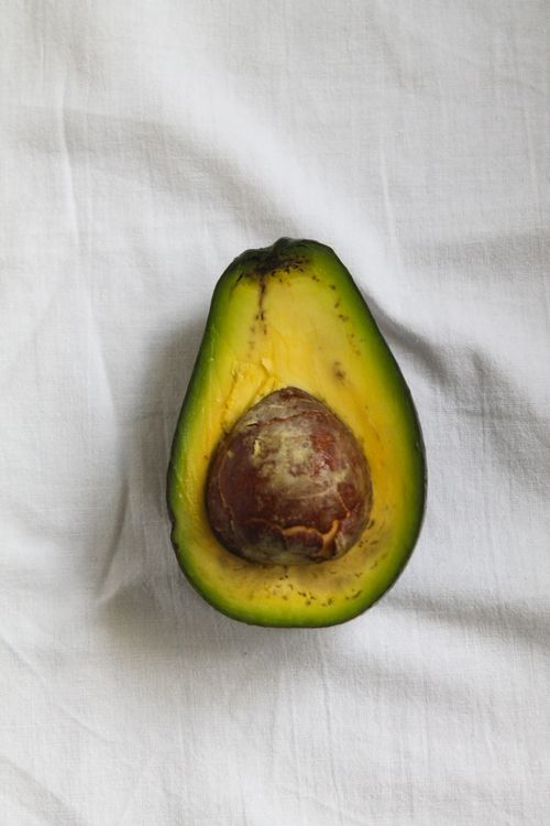 Free Close-up of a ripe avocado half on a white fabric surface, showcasing its vibrant color. Stock Photo