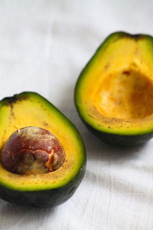 Free Close-up of ripe avocado halves showcasing fresh green flesh and seed against a white background. Stock Photo