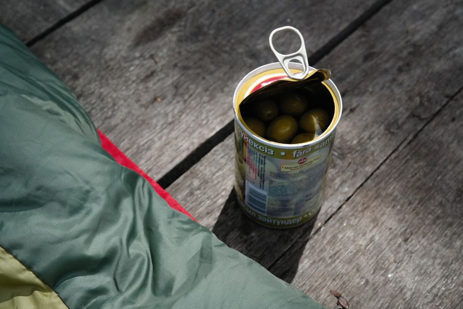 Lata abierta de aceitunas verdes o negras españolas sobre una mesa blanca