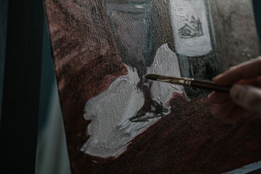 Artist hand painting on canvas with brush, detailed artwork creation in process.
