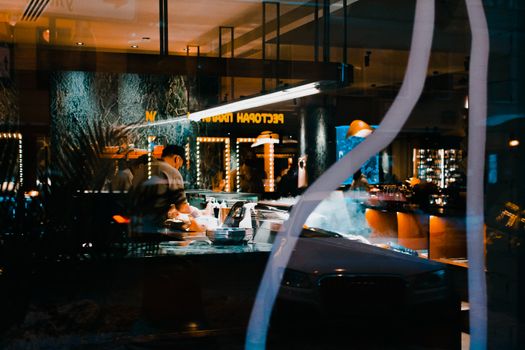Cozy restaurant interior in Saint Petersburg, Russia, captured through a window, showcasing a warm ambiance.