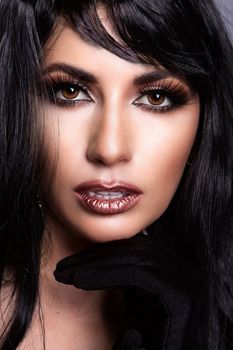 Close-up portrait highlighting bold makeup and styling, featuring a captivating expression with dramatic dark hair.