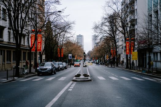A city street featuring parked cars, leafless trees, and high-rise buildings on a quiet winter day.