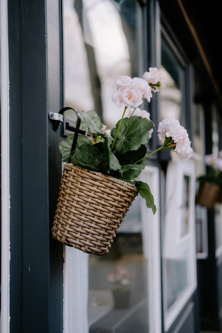 White Flowers In Brown Woven Basket Hanging On Door