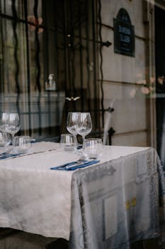 Elegant table setting with glassware and cutlery at an outdoor restaurant, creating a sophisticated dining atmosphere.