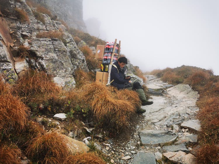 Mountain Porter With Load On Back Resting On Route