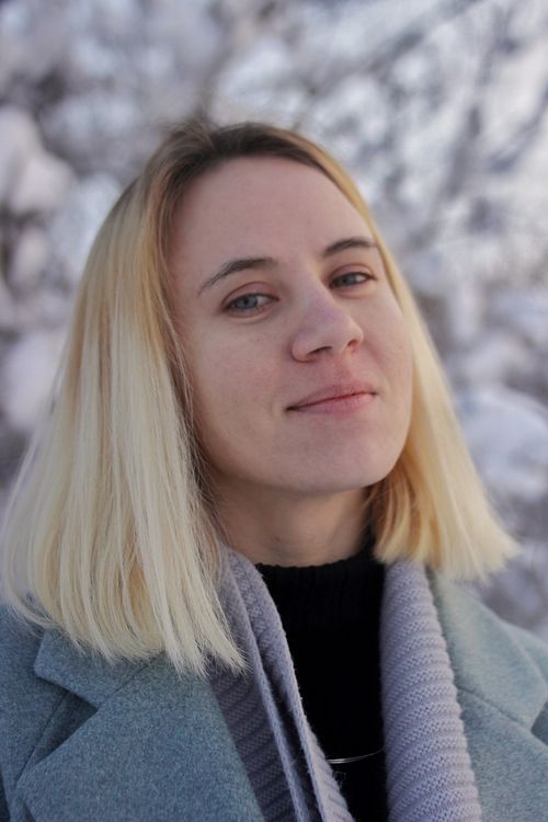 Free A cheerful woman in a winter setting wearing a gray coat and scarf, exuding warmth and confidence. Stock Photo