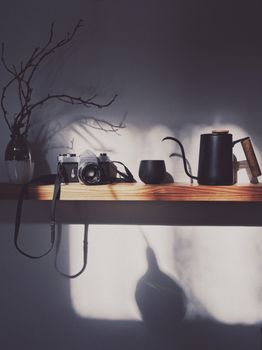 Stylish shelf with a camera, coffee pot, and shadows creating an artistic display.