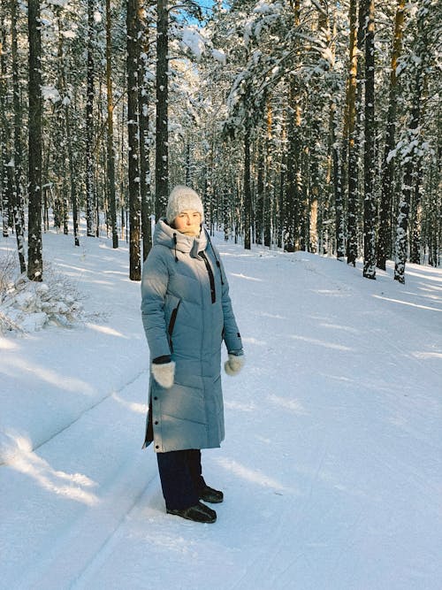 Person in Gray Coat Standing on Snow Covered Ground
