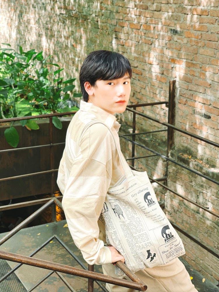 A Man Carrying A Tote Bag Leaning On A Railing