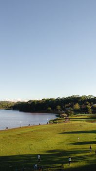 Aerial view of a park with people enjoying recreational activities by the lakeside.