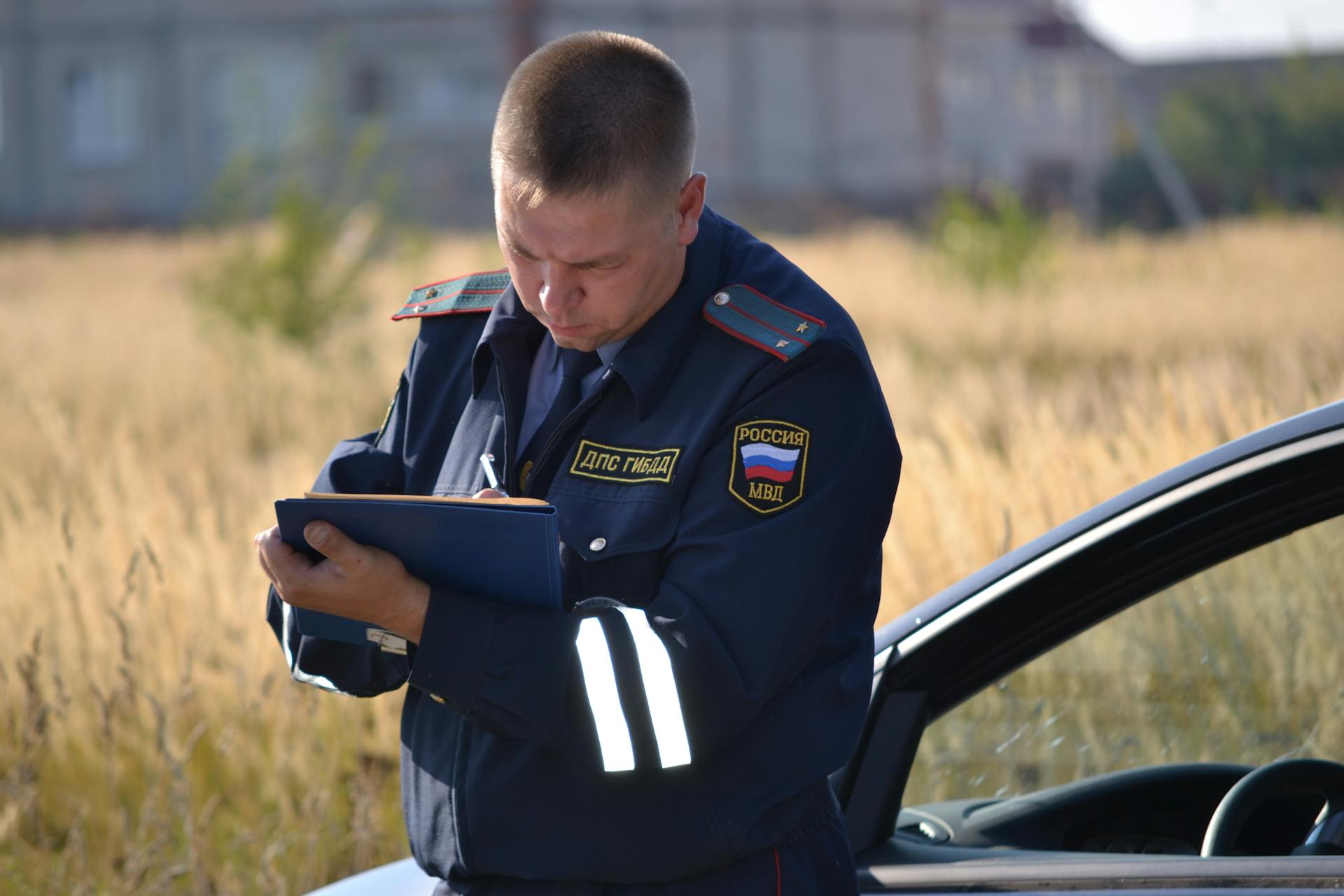 Man in Blue Police Uniform Writing on Folder