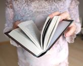 Person Holding Book on Brown and White Floral Textile