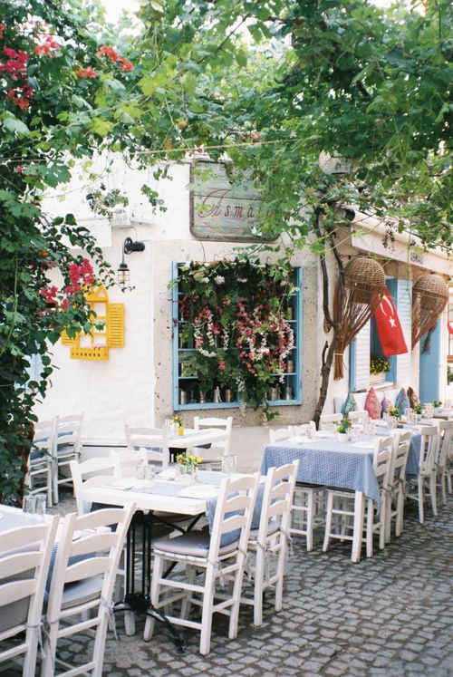 Free Quaint outdoor cafe setting adorned with flowers and Turkish decor in Alaçatı. Stock Photo