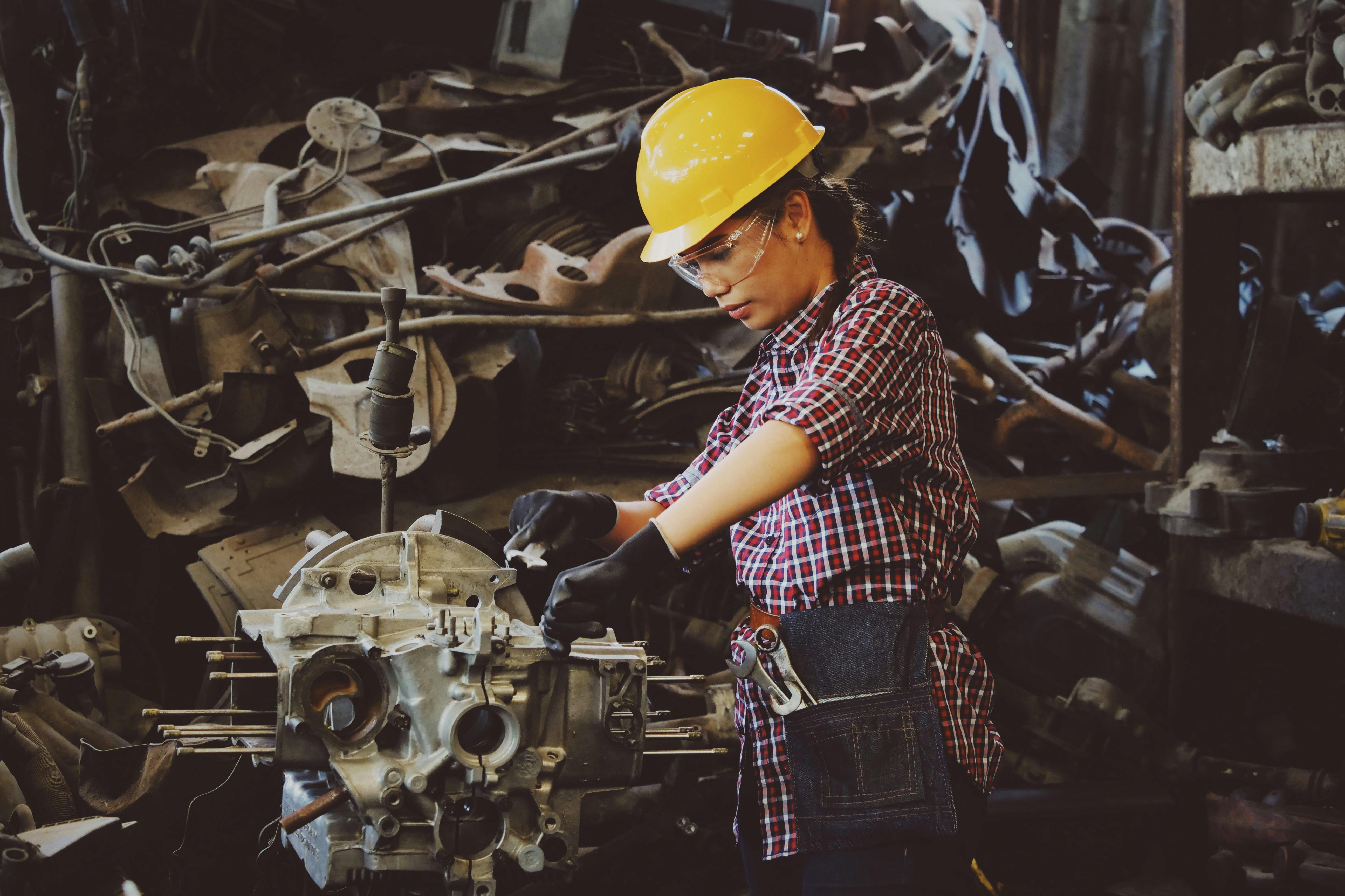 Free Woman Wears Yellow Hard Hat Holding Vehicle Part Stock Photo