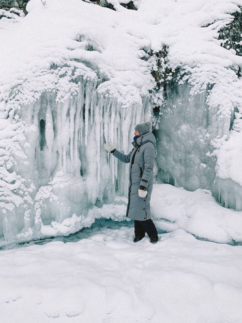 Free A person in winter clothing exploring a snowy landscape with icicles. Stock Photo