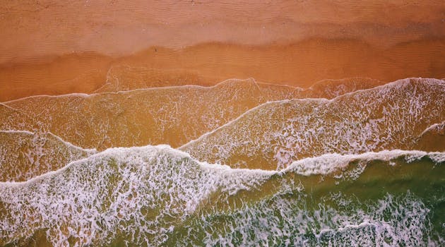 从鸟瞰视角看，海浪拍打沙滩的景象令人惊叹，营造出宁静而优美的沿海景观