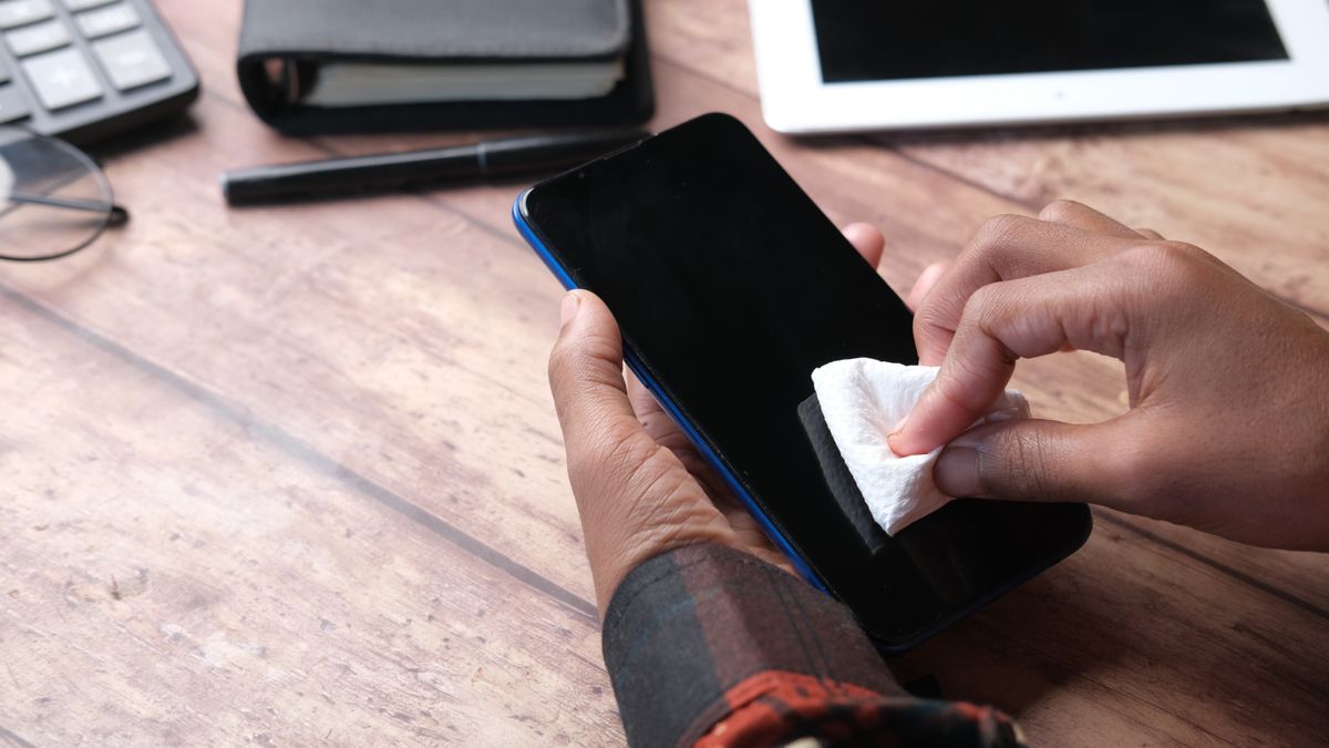 スマートフォンの画面を布で拭いている手元のイメージ