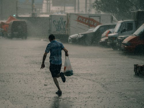 Man Running in the Rain Carrying a Plastic Bag