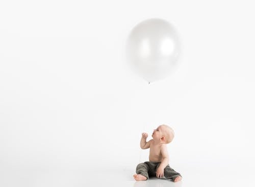 Kostenlos Topless Kleinkind Mit Hosen, Die Auf Weißer Oberfläche Sitzen, Während Sie Nach Oben Schauen Stock-Foto