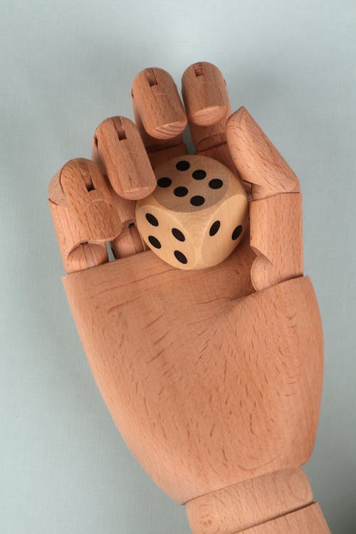 Brown Wooden Hand Holding a Dice