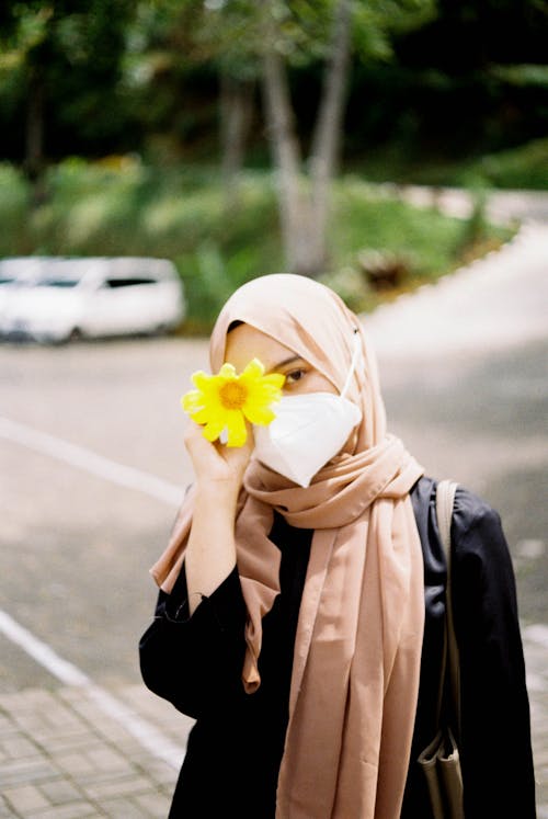 Woman in Brown Hijab Holding a Yellow Flower