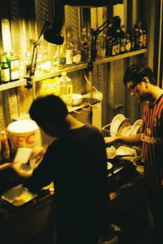 Two men preparing food in a cozy kitchen setting. Warm lighting creates an intimate atmosphere.