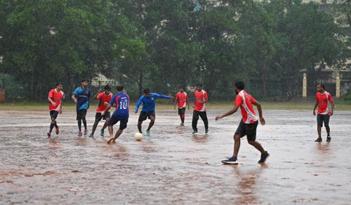 Free Players enjoying an intense soccer game in the rain on an open field in Kerala, India. Stock Photo