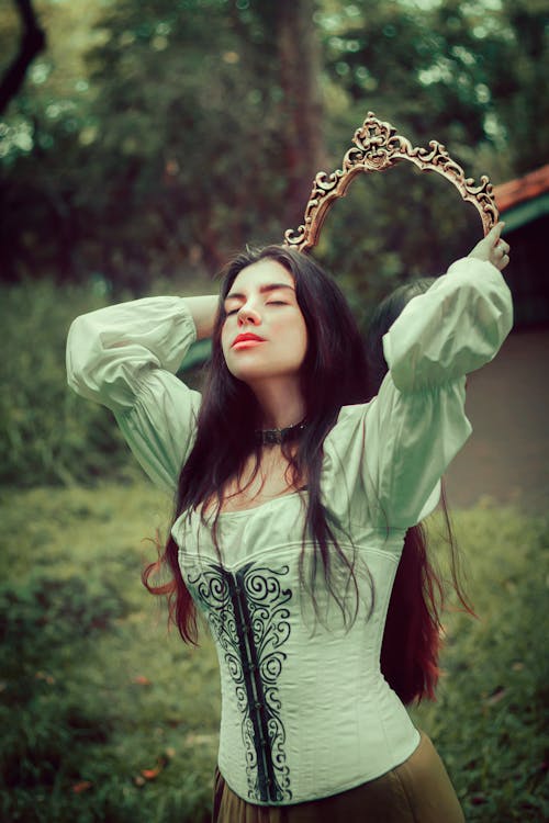 Photo of a Woman Holding a Mirror Behind Her Hed