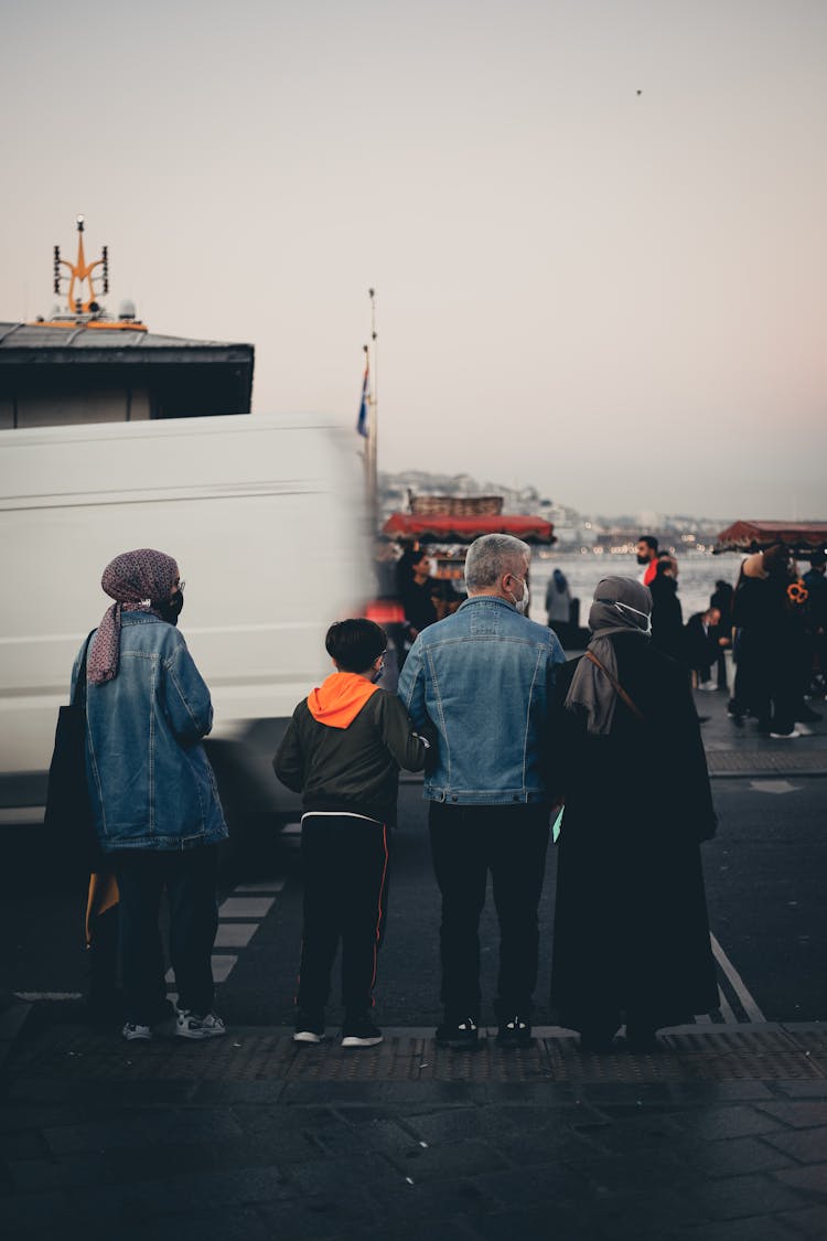 Back View Of A Family Standing On The Side Of The Road 