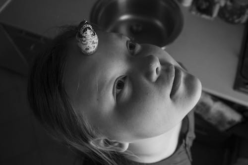Portrait of Little Girl Holding Matryoshka Doll on her Forehead