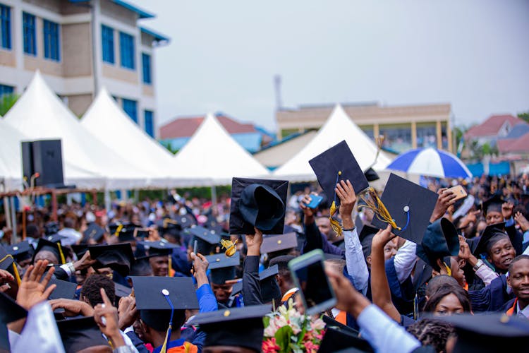 Crowd Of Students Holding Up Their Graduation Caps