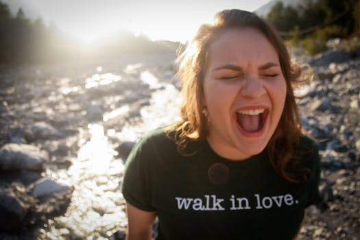 白天，一名年轻女子在岩石小溪旁深情地笑着