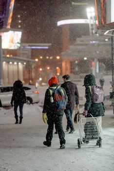 People walking in a snowy city street at dusk, showcasing winter's chill.