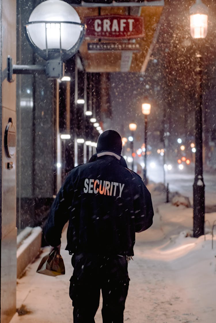 Person In Black Jacket Walking On Sidewalk Covered With Snow