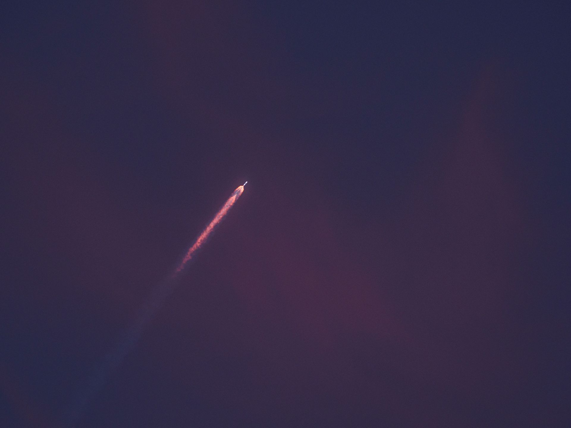 Long-exposure shot of a rocket rising into a night sky