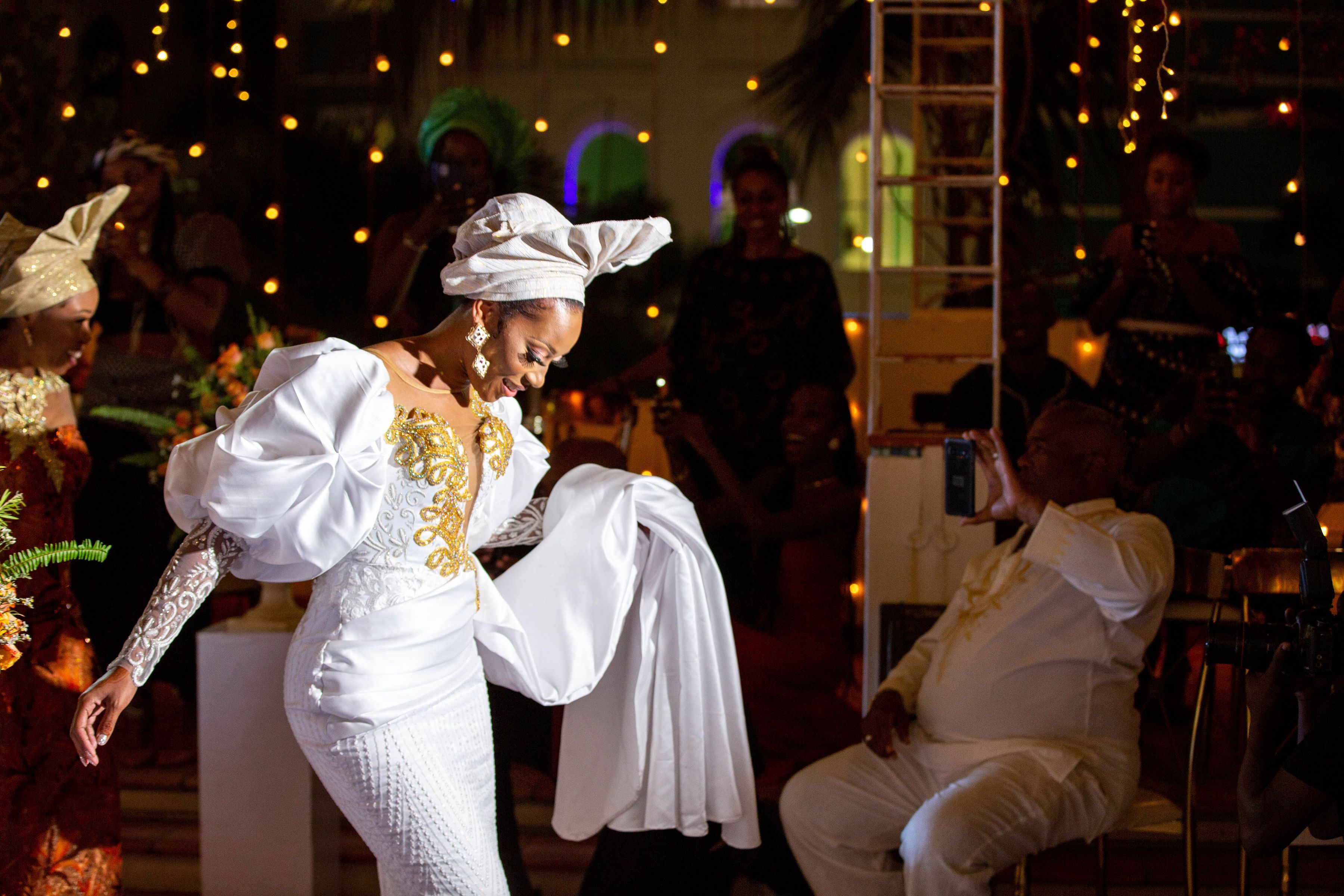 Bride in white dress gracefully dancing at a vibrant wedding celebration with joyful guests.
