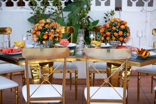 Free A beautifully set outdoor table with vibrant floral centerpieces and gold chairs creates a luxurious dining atmosphere. Stock Photo