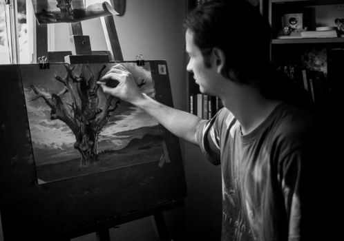 A focused artist painting a tree on canvas in a studio setting.